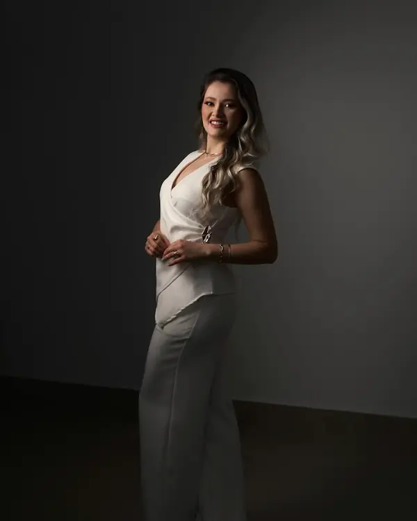 Luciana Buss de corpo inteiro, de branco, sorrindo